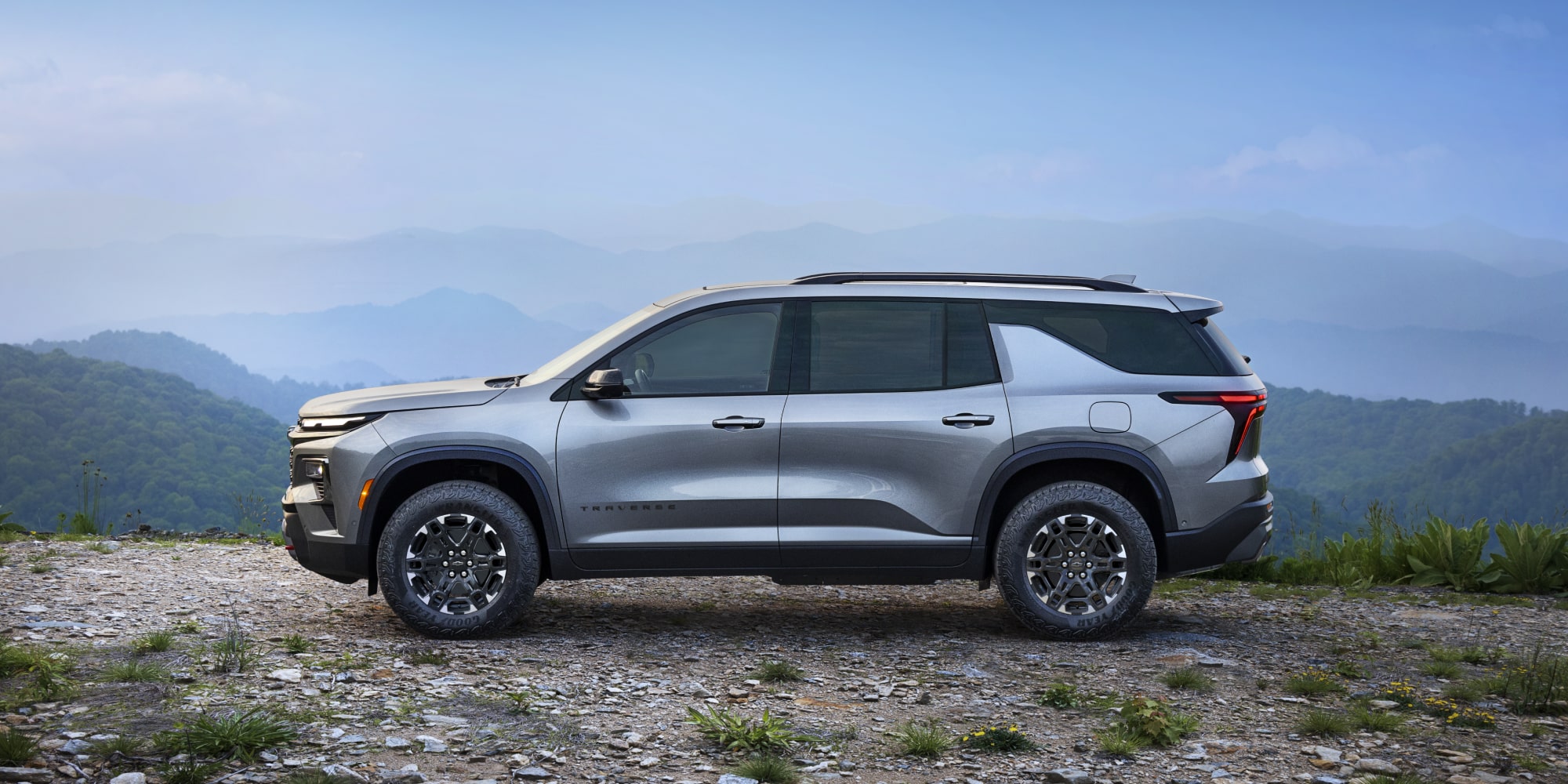 Vue latérale d’une Chevrolet Traverse 2027 stationnée sur un terrain accidenté.