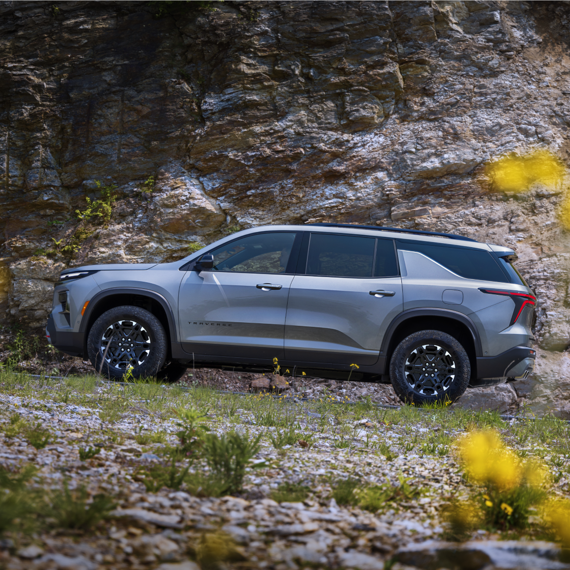 Vue latérale de la Chevrolet Traverse 2027 stationnée sur un terrain rocheux.