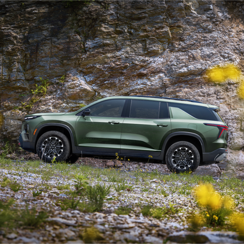 Vue latérale de la Chevrolet Traverse 2027 stationnée sur un terrain rocheux.