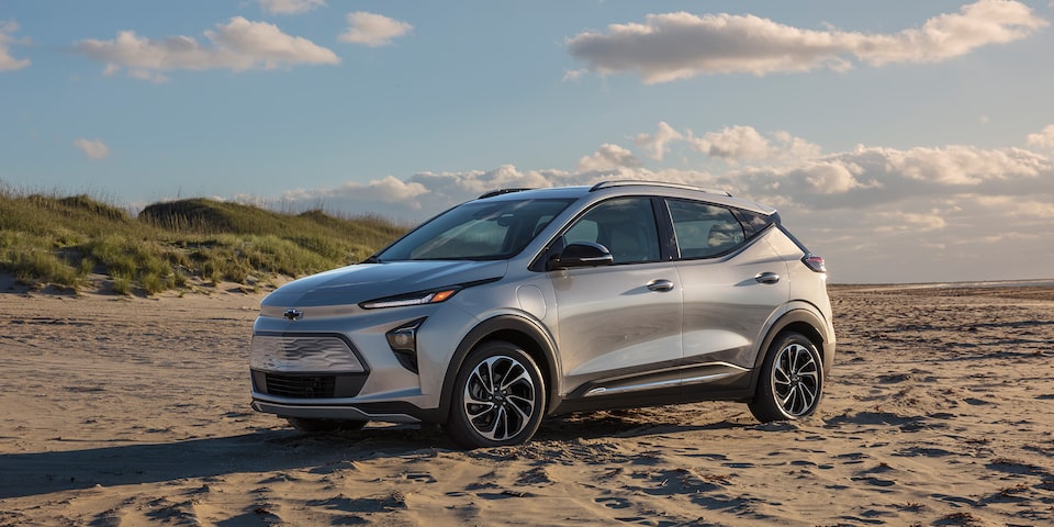 Vue latérale avant côté conducteur du Bolt EUV 2023 stationné sur une plage sablonneuse.