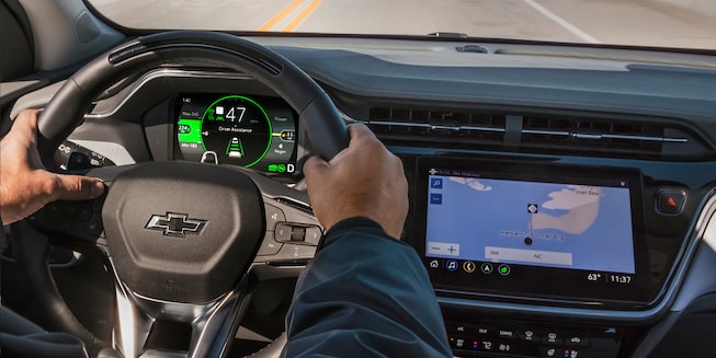 Les mains du conducteur sur le volant du Bolt EUV 2023 avec le système de navigation.