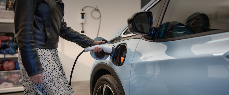 Vue rapprochée d’une personne qui branche une Bolt EV 2023 pour la recharger.