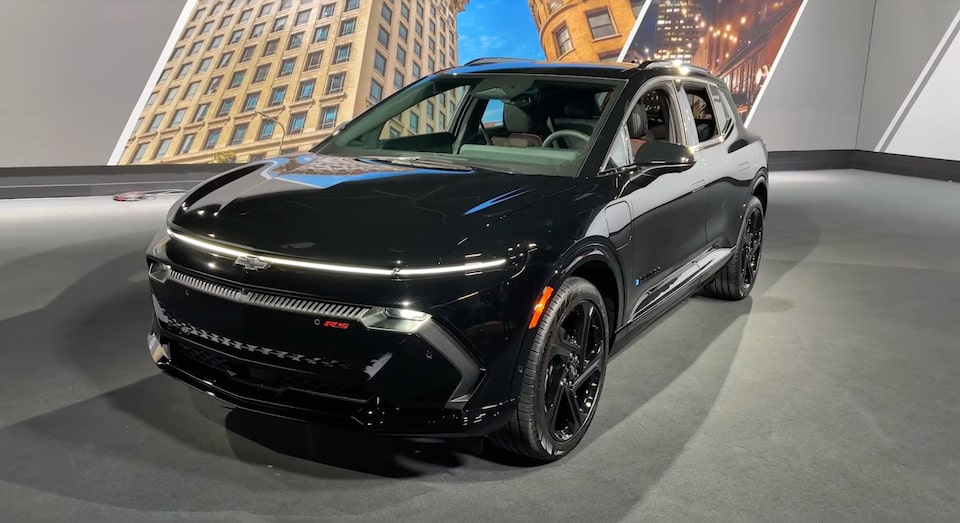 Vue latérale avant d’un Chevrolet Equinox EV noir stationné à l’intérieur.