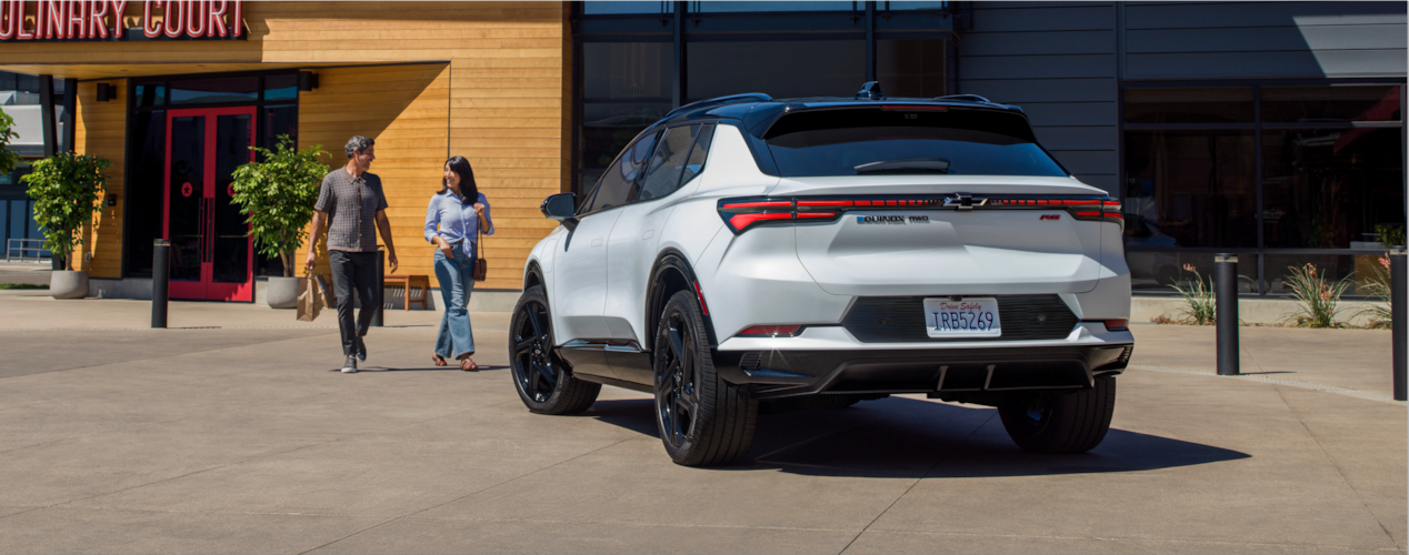 Two people outside a restaurant walking towards a Chevrolet Equinox EV together.