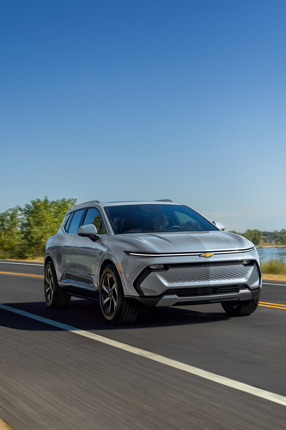 Front-side view of a 2025 Chevrolet Equinox EV driving down the road.