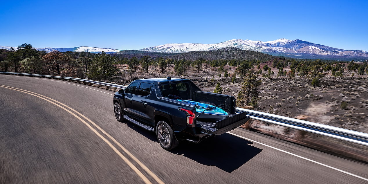 Back-side view of a 2025 Chevrolet Silverado EV driving on a mountainside road.