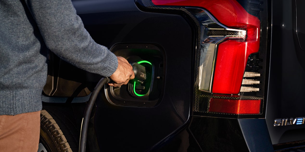 A person charging the 2025 Chevrolet Silverado EV on a sunny day.