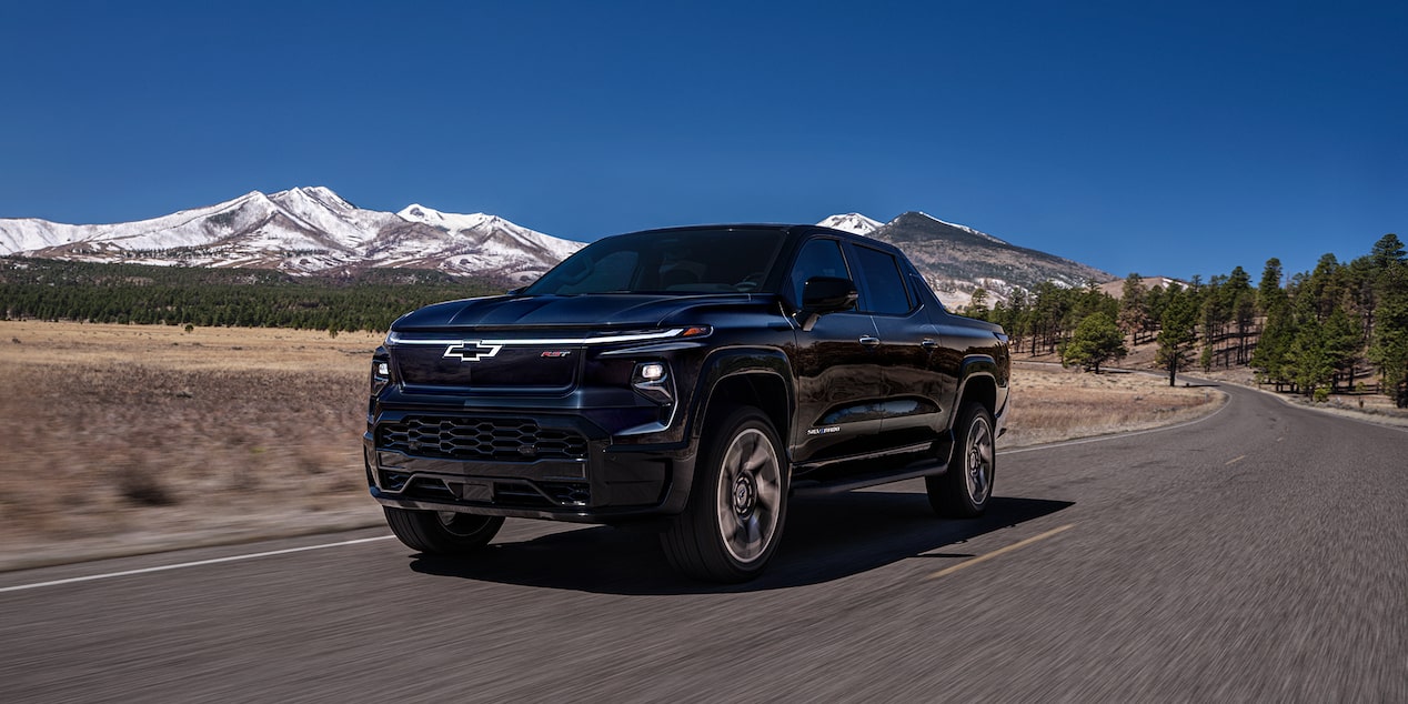 Front-side view of a 2025 Chevrolet Silverado EV driving alone on a country road.