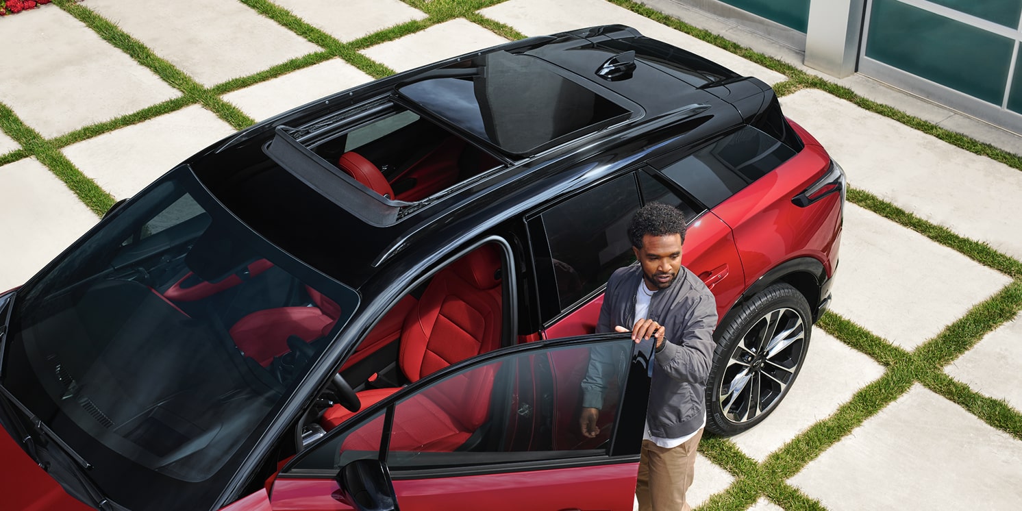 Un homme entre dans le Chevrolet Blazer EV 2026 pendant qu’il est stationné dans une entrée.