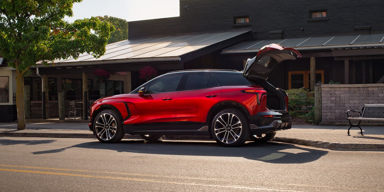 Vue latérale d’un Chevrolet Blazer EV 2026 dont le coffre est ouvert stationné devant une boutique.