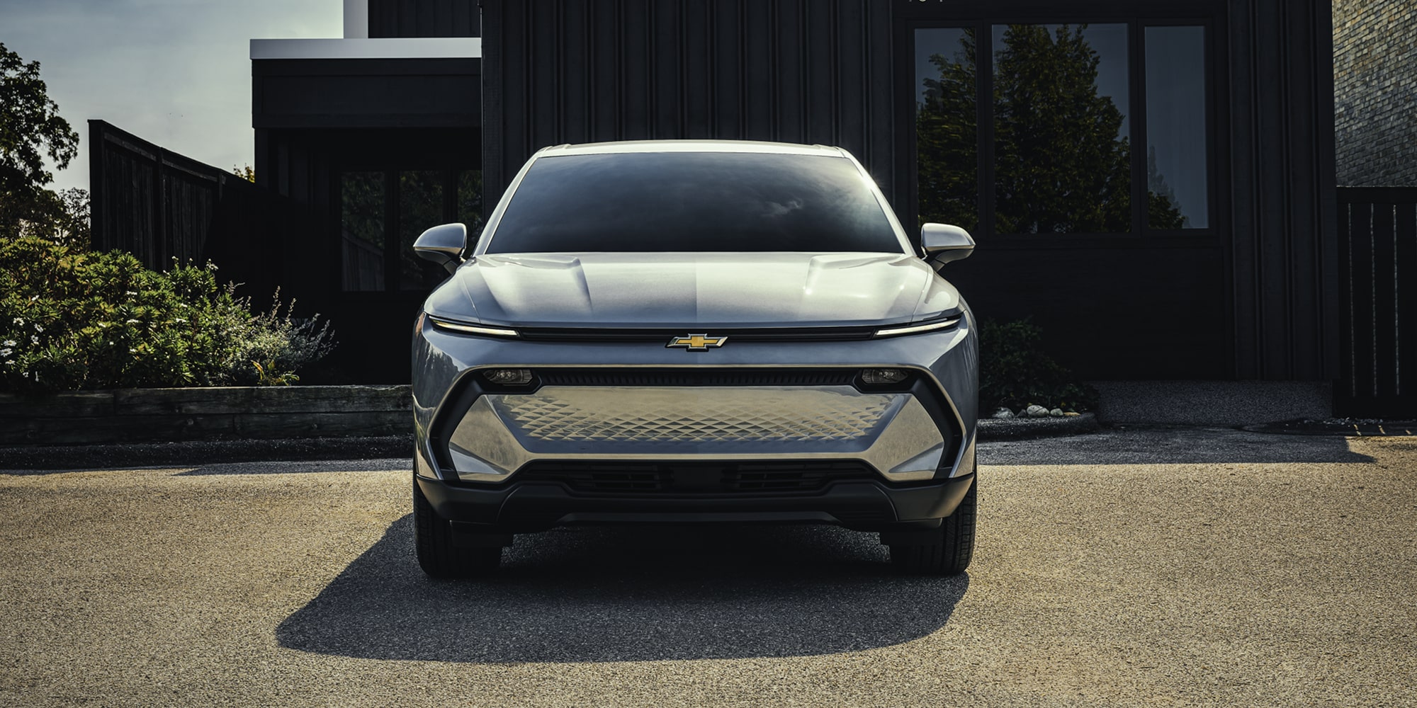 Official image of a blue 2026 Chevrolet Equinox EV driving beside a lake