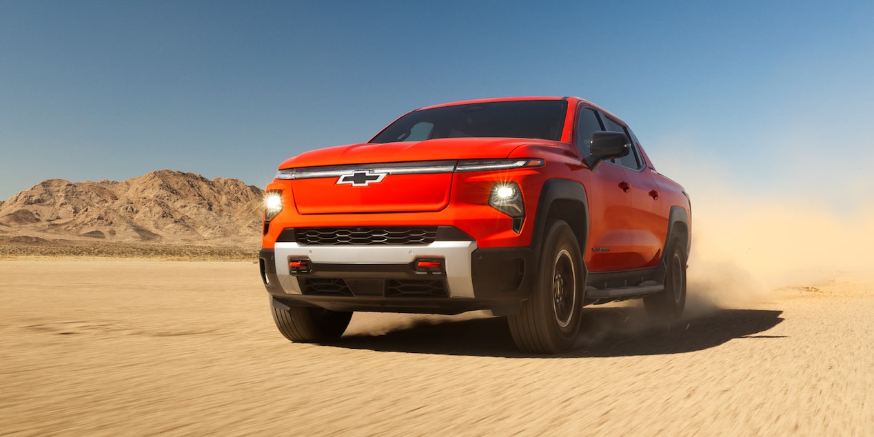 Front-side view of the 2026 Chevrolet Silverado EV driving in the middle of a Desert.
