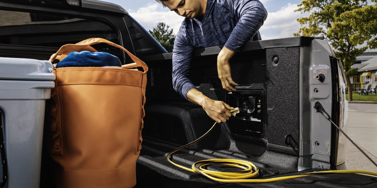 A person inserting an electrical plug in the Charging Port of the 2026 Chevrolet Silverado EV.