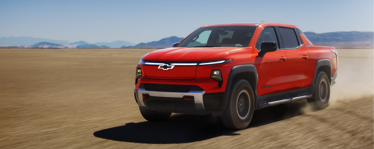 Un Chevrolet Silverado EV 2026 en mouvement sur la terre battue avec des montagnes au loin.