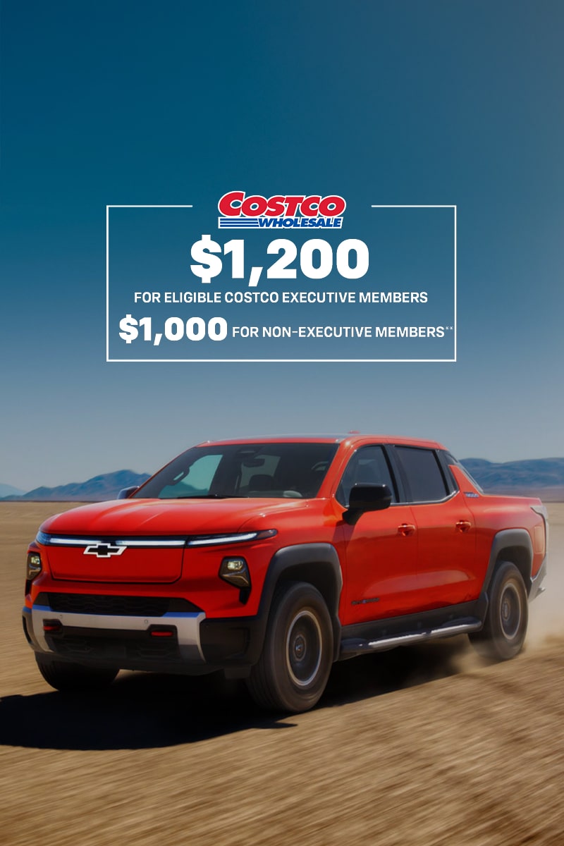 2026 Silverado EV Driving on a Dirt Terrain With Mountains in the Distance.