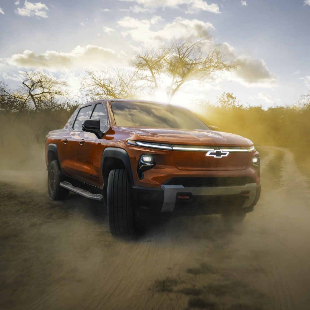 2026 Chevrolet Silverado EV Driving Alone on a Dirt Road in the Woods.