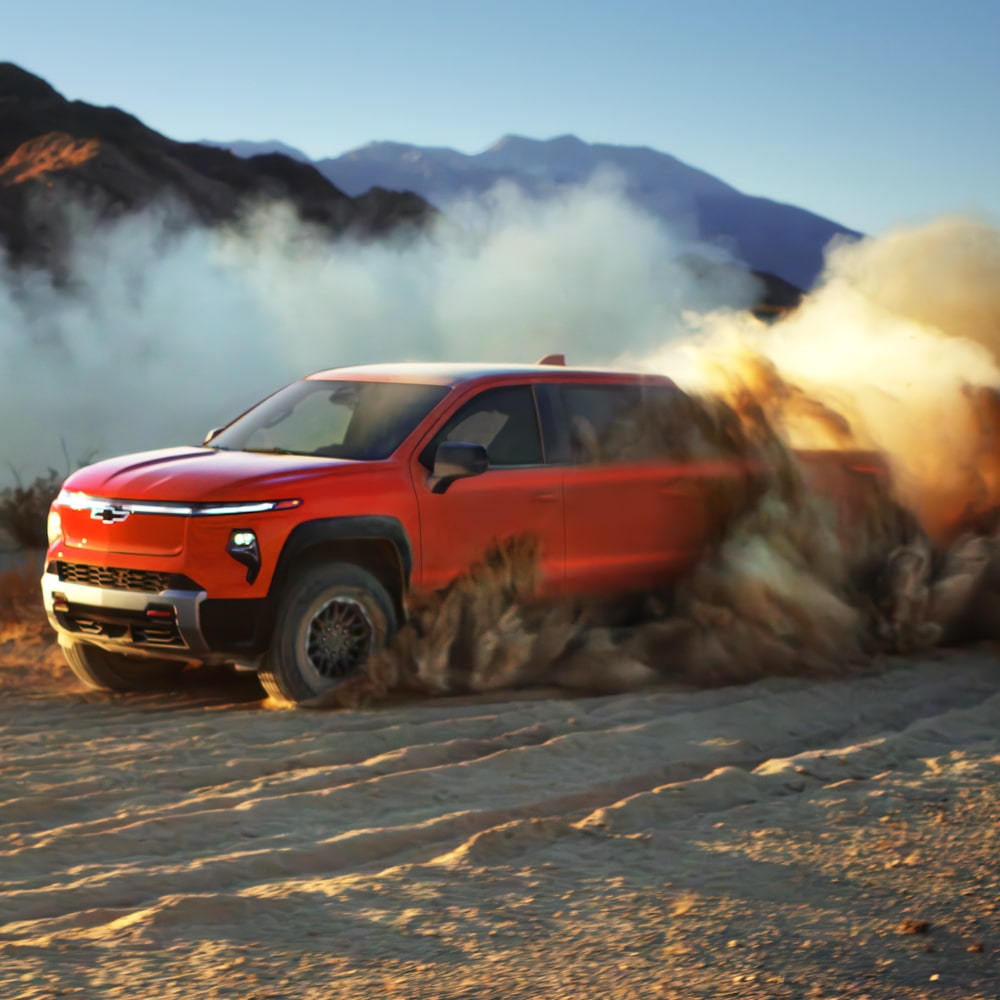 2026 Chevrolet Silverado EV skidding on a dusty terrain.
