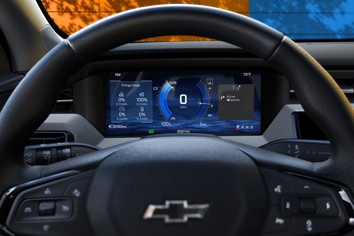 The Interior of a 2027 Chevrolet Bolt Shows the Driver's Perspective of the Digital Display Screen behind the Steering Wheel, with a Small Part of the Orange and Blue Exterior Visible through the Windshield.