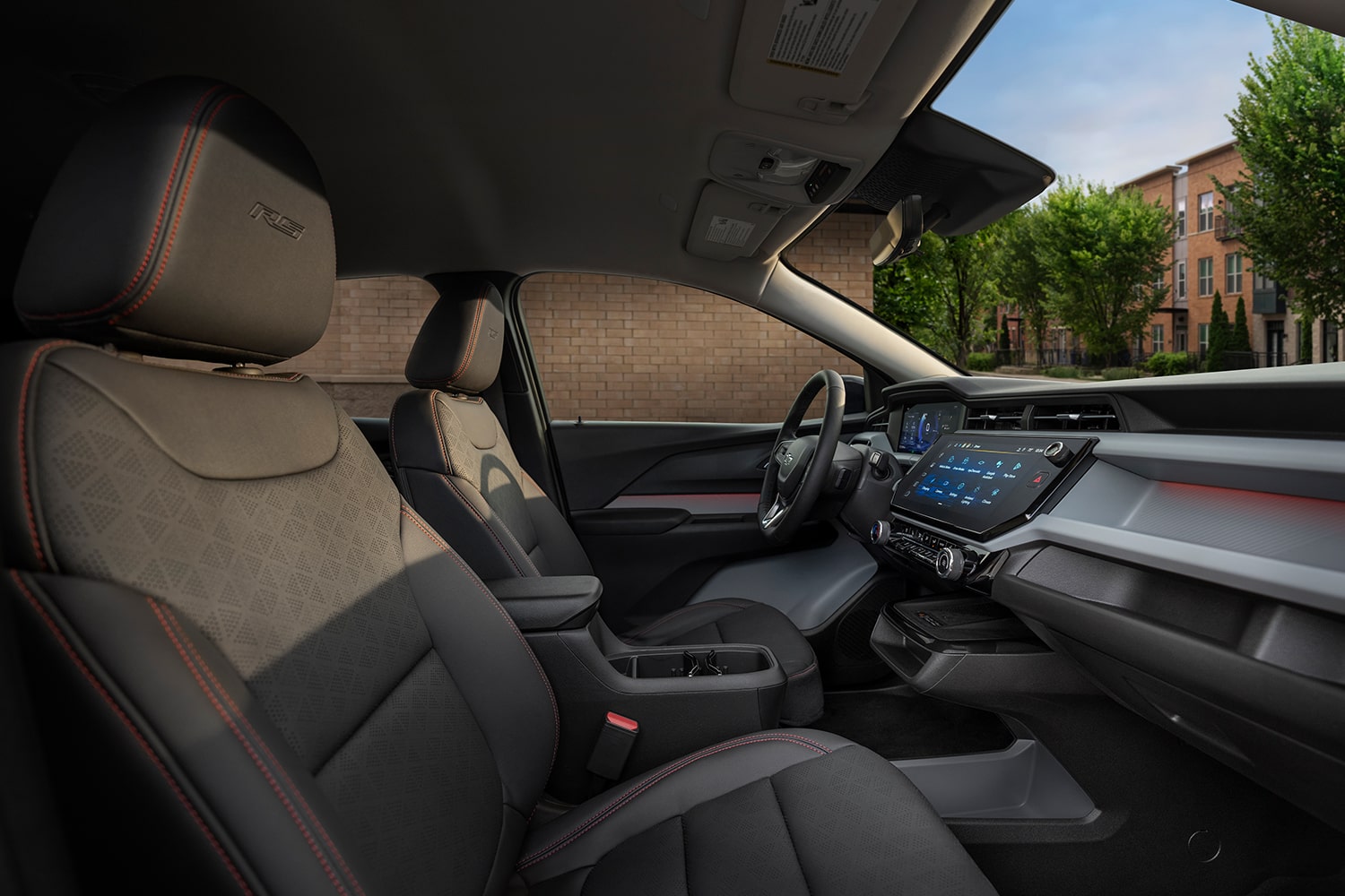 The Interior of a 2027 Chevrolet Bolt RS, Showing the Black and Gray Leather-Trimmed Front Seat with Red Stitching and the RS Badge on the Headrest.