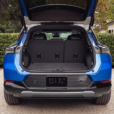 Rear View of a Blue Equinox EV with Truck Open Parked on a Gravel Driveway