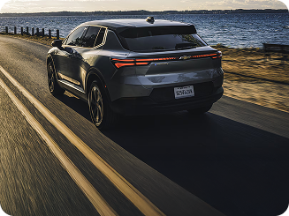 Rear View of a Silver Equinox EV Driving on Highway Along the Water