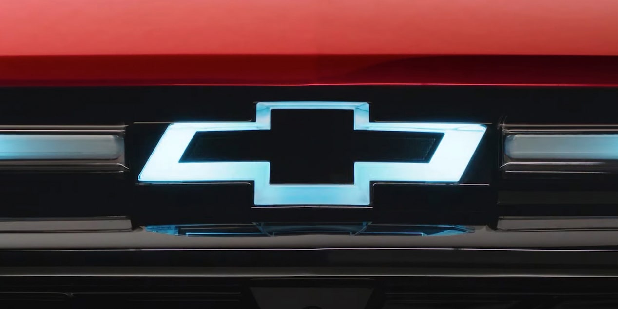 Close up view of the Chevrolet emblem on the front grille of a Chevrolet EV lighting up.