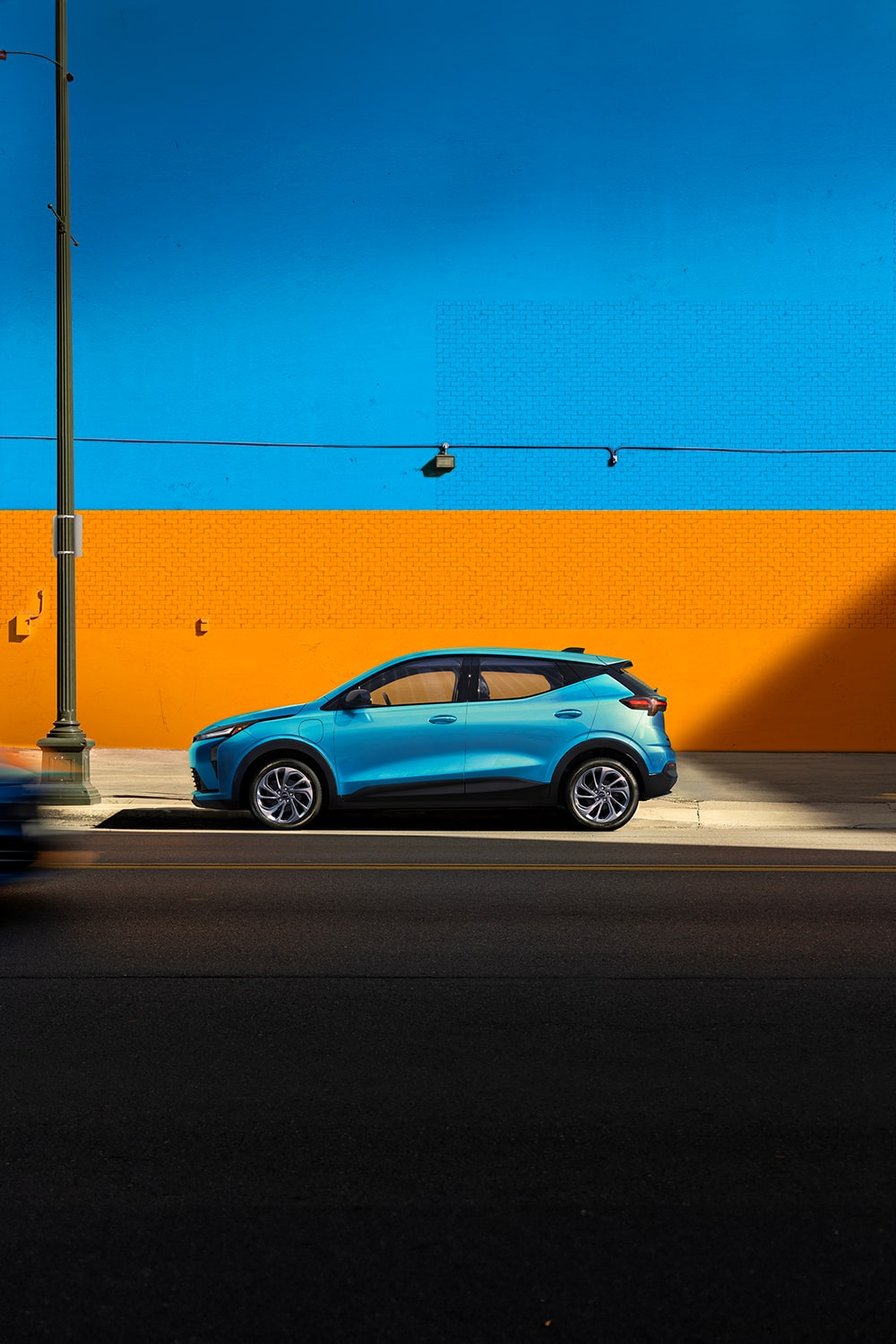 Vue latérale du VÉ Chevrolet Bolt 2027 stationné devant un mur orange.
