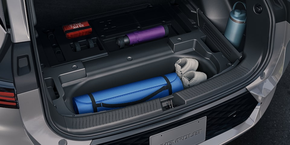 Des articles de sport sont rangés dans le coffre d’un VÉ Chevrolet argenté.