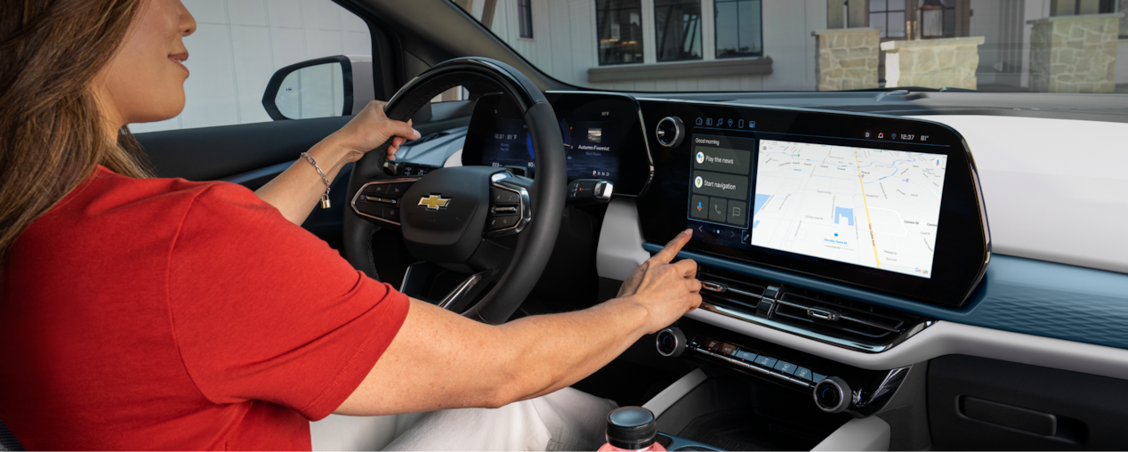 A driver pressing the Infotainment Screen with Google Built-In compatibility inside a Chevrolet EV.
