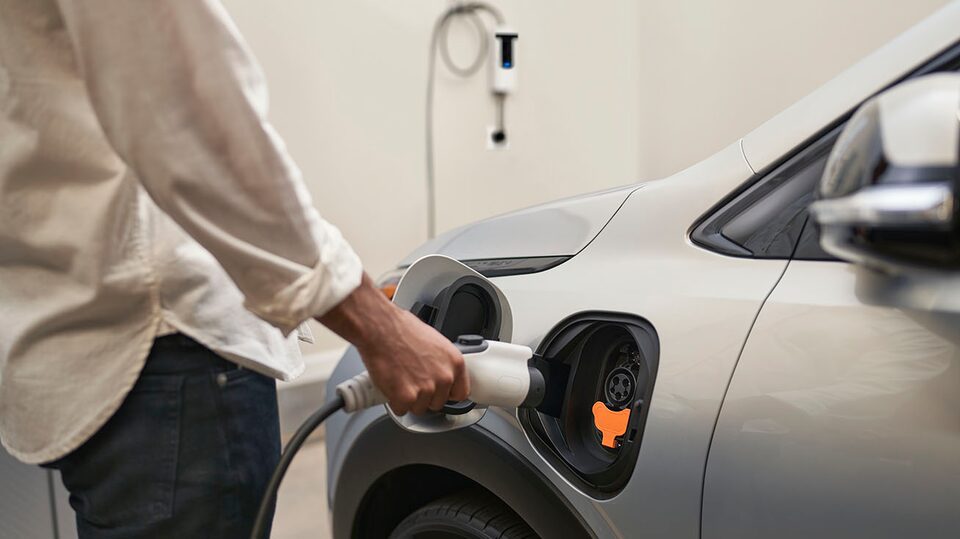 Une personne recharge son VÉ Chevrolet à un port de recharge électrique.