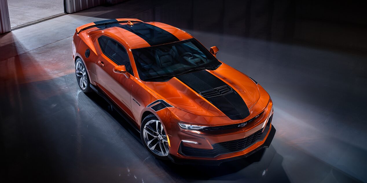 Vue aérienne de la Chevrolet Camaro 2024 en orange vif métallisé stationnée dans un entrepôt.