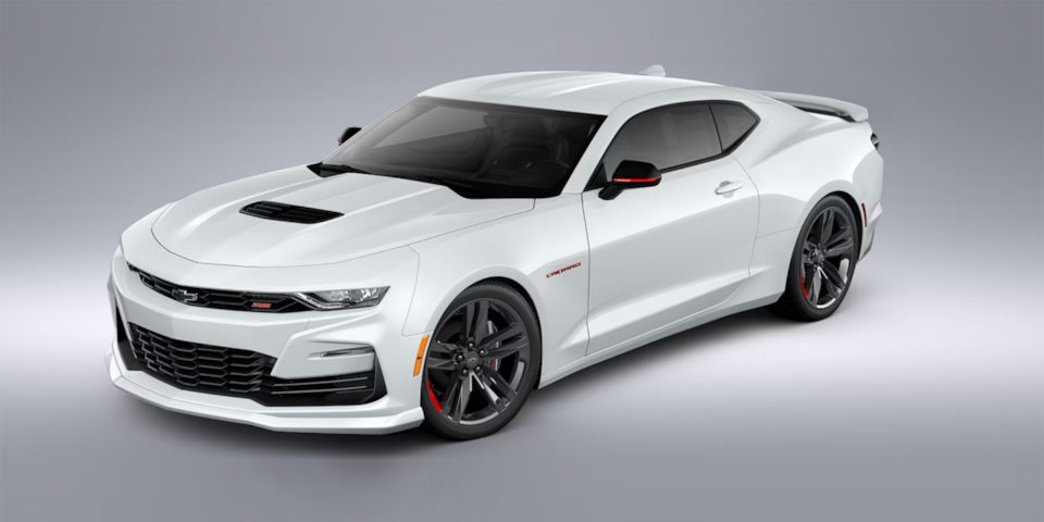Vue latérale avant de la Chevrolet Camaro 2024 en blanc sommet stationnée dans une salle d’exposition.
