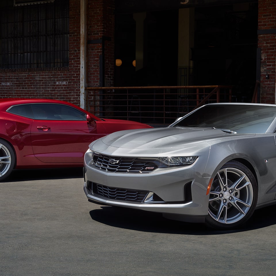 Deux Chevrolet Camaro 2024 stationnées devant un bâtiment.