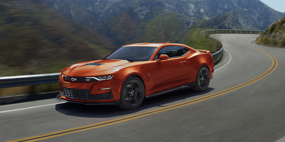Une Chevrolet Camaro 2024 en orange vif métallisé en mouvement sur une route panoramique.