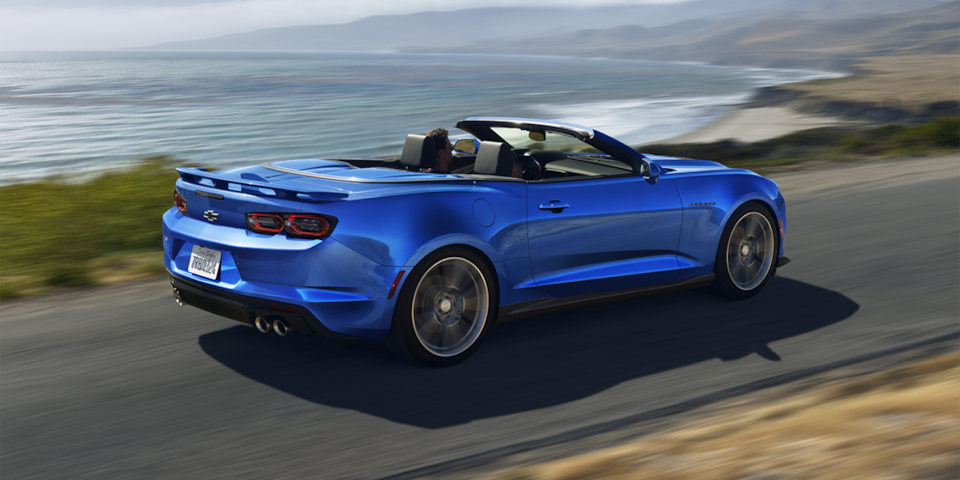 Chevrolet Camaro 2024 en bleu déferlante en mouvement sur une route côtière.