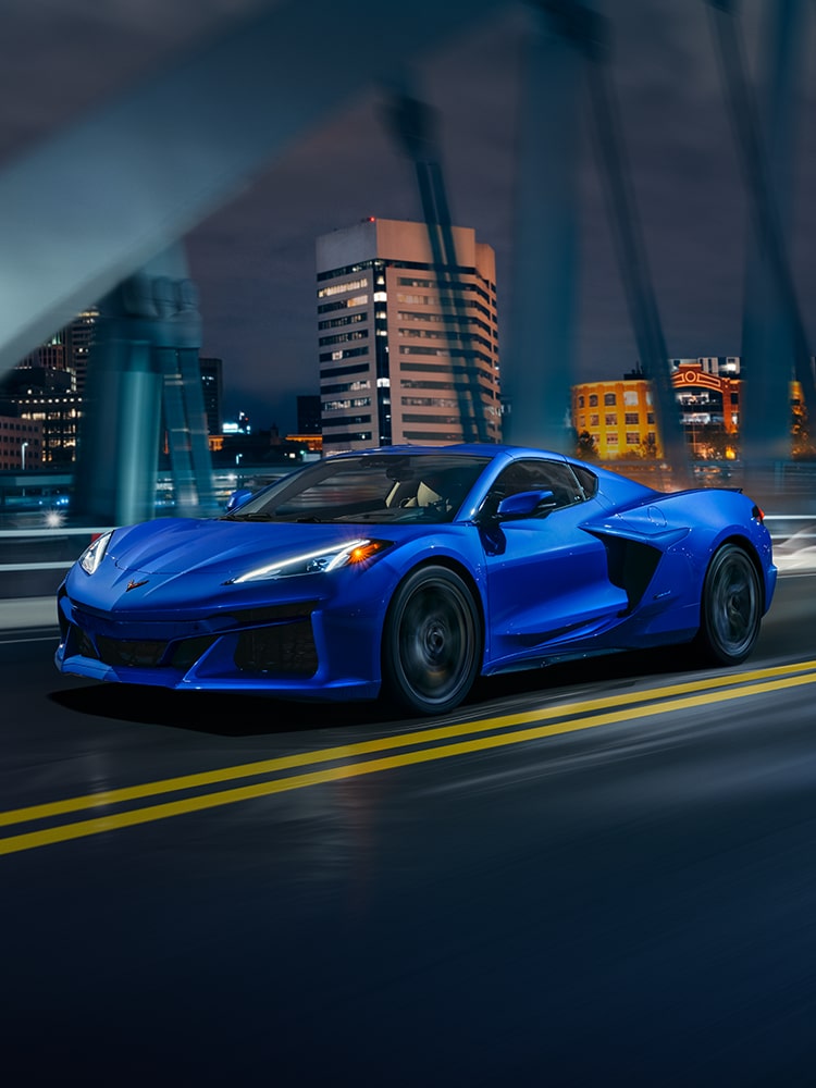 Three Quarters View of a 2026 Chevrolet Corvette E-Ray Driving Down the Bridge at Night.
