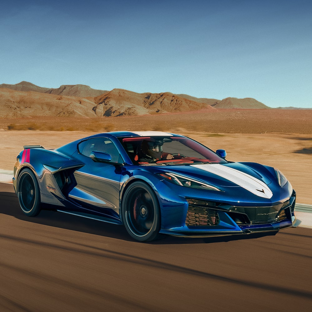 The 2027 Chevrolet Corvette Grand Sport in Blue with a White Stripe Driving Down a Track in the Desert.