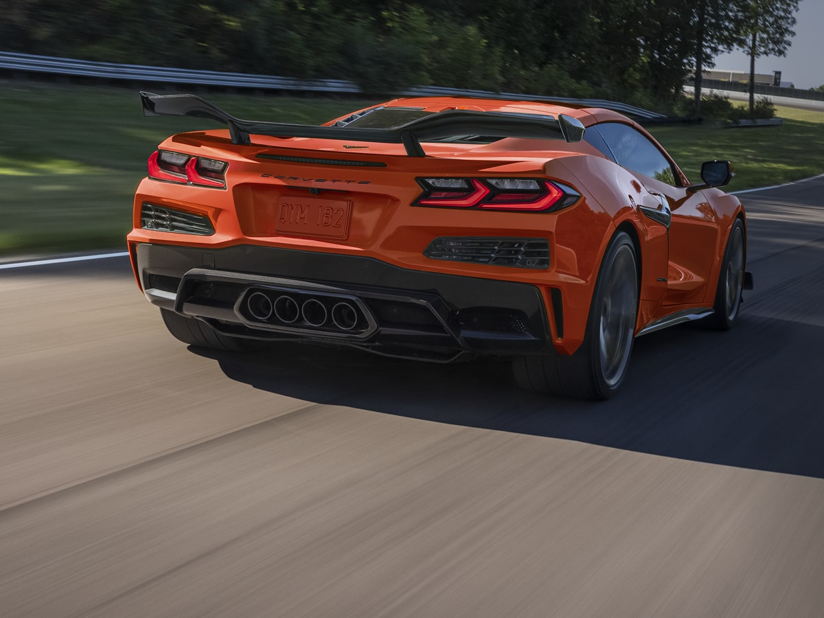 Vue arrière de la Chevrolet Corvette Z06 2027 roulant à vive allure sur une route bordée d'arbres.