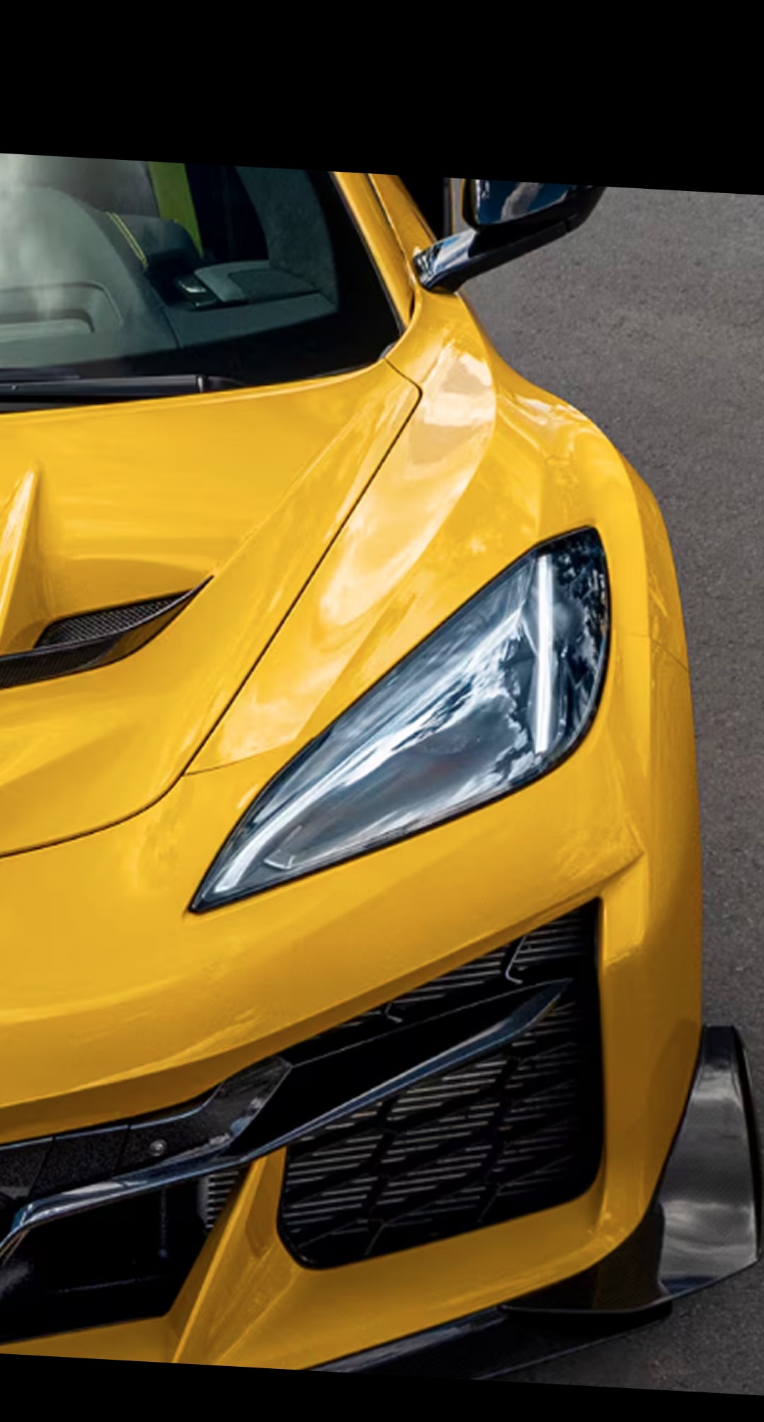 Vue rapprochée du coin avant d’une Chevrolet Corvette ZR1 jaune 2027 stationnée sur une route pavée.