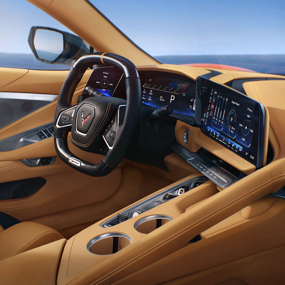 Une vue large sur l’intérieur de la Chevrolet Corvette ZR1X 2027 avec des sièges en cuir beige et un affichage numérique incurvé sur le tableau de bord.