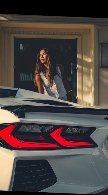 Gros plan du feu arrière de la Corvette Stingray 2027 avec une femme en arrière-plan.