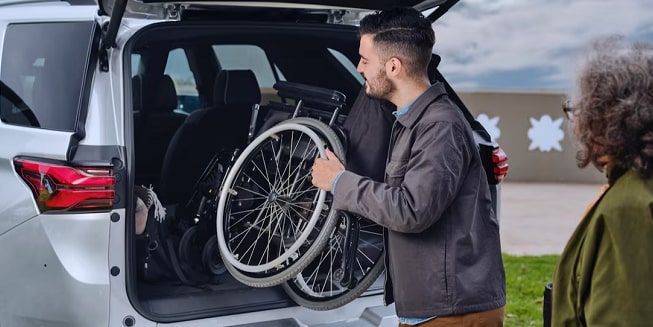 A man carrying a wheelchair for someone eligible for GM’s Mobility Program.