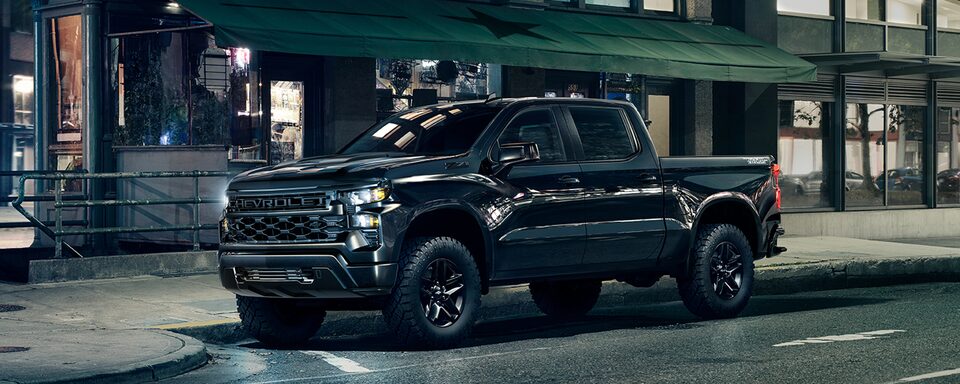 Front driver shot of the 2022 Chevrolet Silverado Custom Trail Boss Midnight Edition with headlamps on.