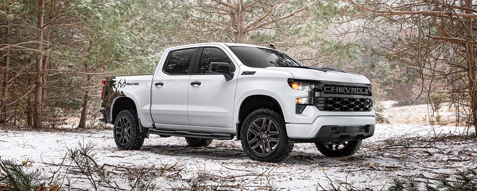 Front passenger shot of the 2022 Chevrolet Silverado Realtree Edition in a snowy forest.