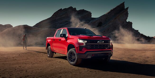 2023 Chevrolet Silverado pickup truck moving on dusty terrain.