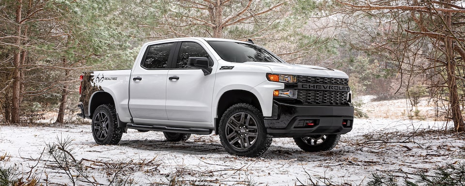 Front passenger shot of the 2023 Chevrolet Silverado Realtree Edition in a snowy forest.