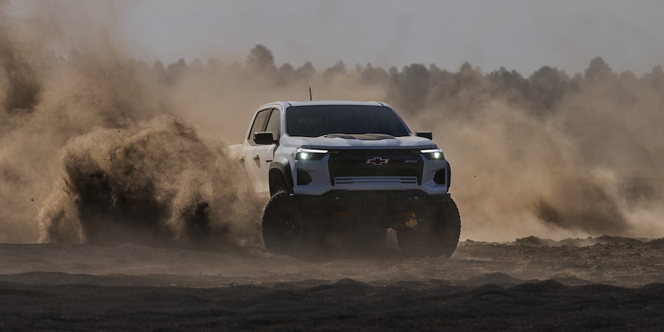 The Colorado Driving Through the Sand with a Forest in the Background