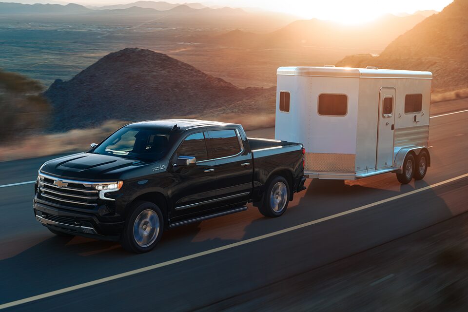 Chevrolet Silverado 2024 qui tire une remorque sur une route à flanc de montagne.