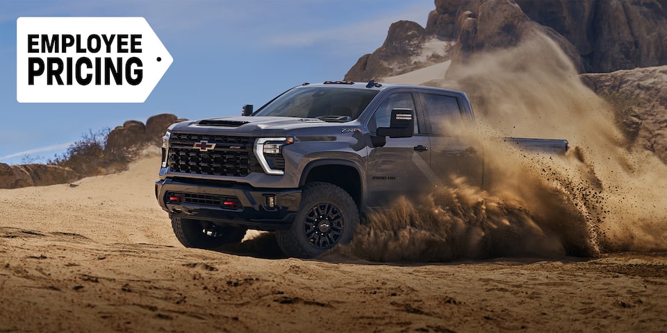 Front-side view of the 2025 Chevrolet Silverado HD pickup truck skidding in a sandy terrain.