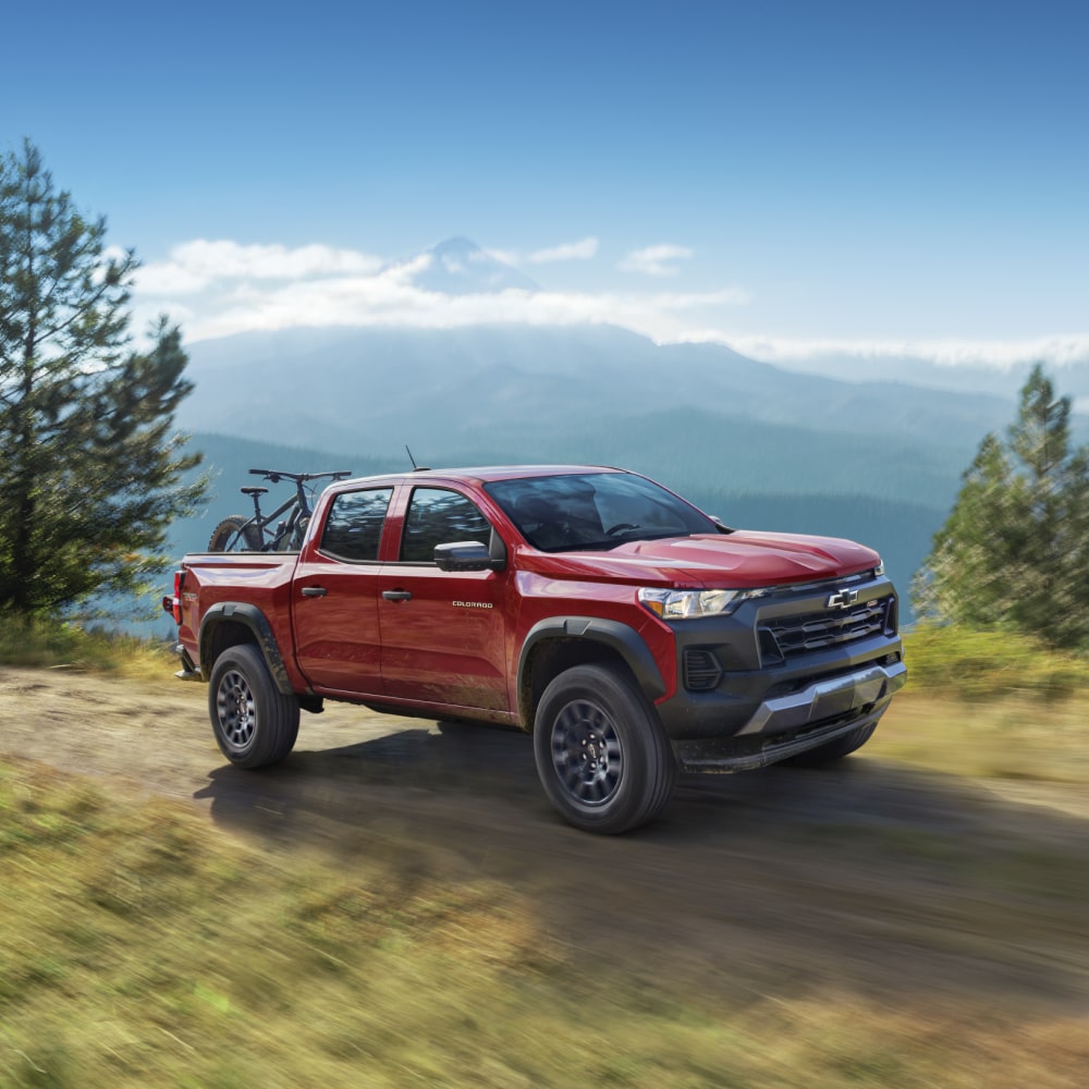 Three Quarters View of a Red 2026 Chevrolet Colorado Driving on a Cliff Road.